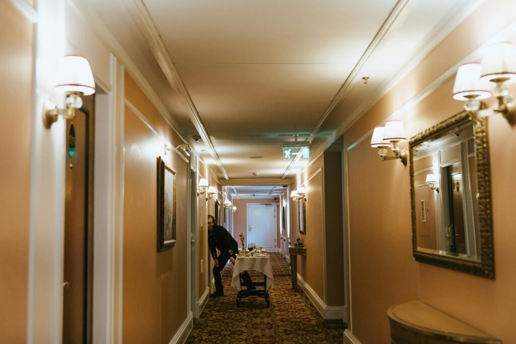 A hotel hallway with a staff member and room service trolley near guest rooms.